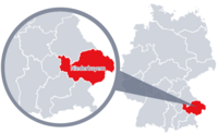 Diese Grafik zeigt eine Karte von Deutschland mit einer detaillierten Ansicht der Region Niederbayern. Niederbayern ist in Rot hervorgehoben und liegt im südlichen Teil Deutschlands. Ein Lupensymbol vergrößert diesen Bereich, um die Lage genauer darzustellen. 