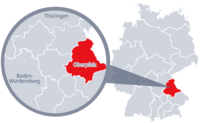 Diese Grafik zeigt eine Karte von Deutschland mit einer detaillierten Ansicht der Region Oberpfalz. Oberpfalz ist in Rot hervorgehoben und liegt im südlichen Teil Deutschlands. Ein Lupensymbol vergrößert diesen Bereich, um die Lage genauer darzustellen. 