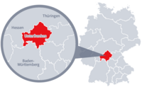 Diese Grafik zeigt eine Karte von Deutschland mit einer detaillierten Ansicht der Region Unterfranken. Unterfranken ist in Rot hervorgehoben und liegt im südlichen Teil Deutschlands. Ein Lupensymbol vergrößert diesen Bereich, um die Lage genauer darzustellen. 
