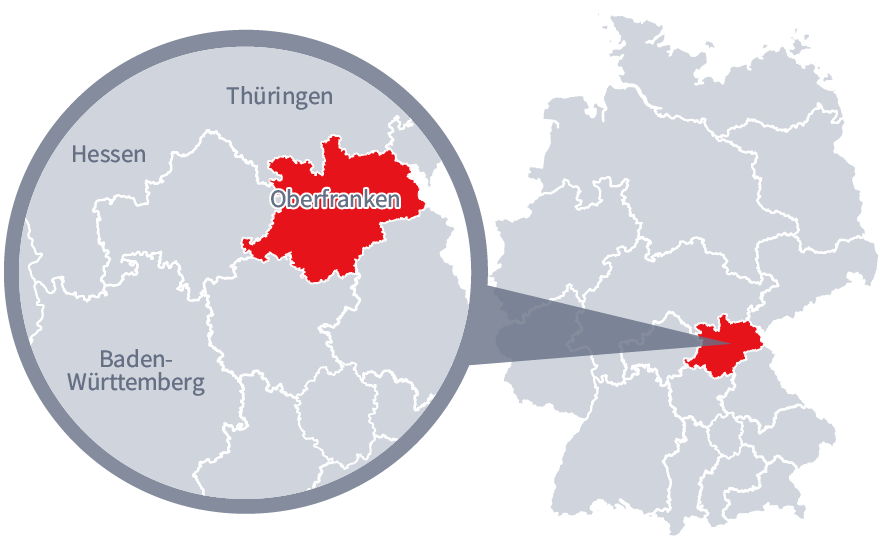Diese Grafik zeigt eine Karte von Deutschland mit einer detaillierten Ansicht der Region Oberfranken. Oberfranken ist in Rot hervorgehoben und liegt im südlichen Teil Deutschlands. Ein Lupensymbol vergrößert diesen Bereich, um die Lage genauer darzustellen. 